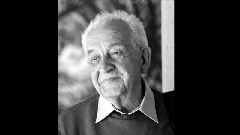 Czarno-białe zdjęcie. Twarz uśmiechniętego siwego starszego mężczyzny