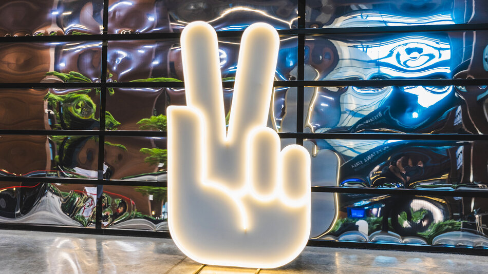 neon przedstawiający rękę z uniesionymi w górę dwoma palcami