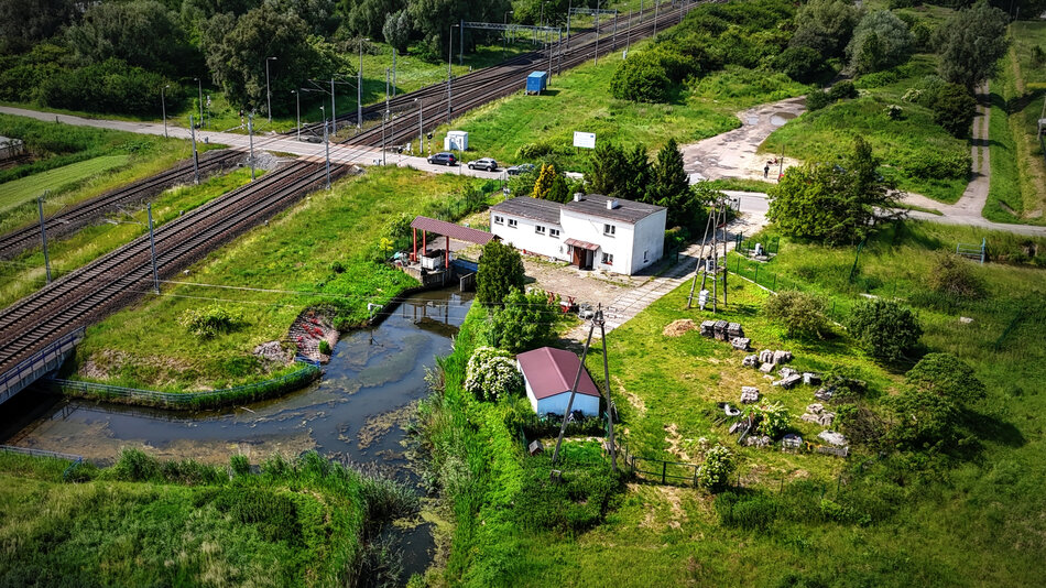 zdjęcie z drona, widać zielony teren z trawami, częściowo z sadzawkami, jest też niewielki jasny budynek