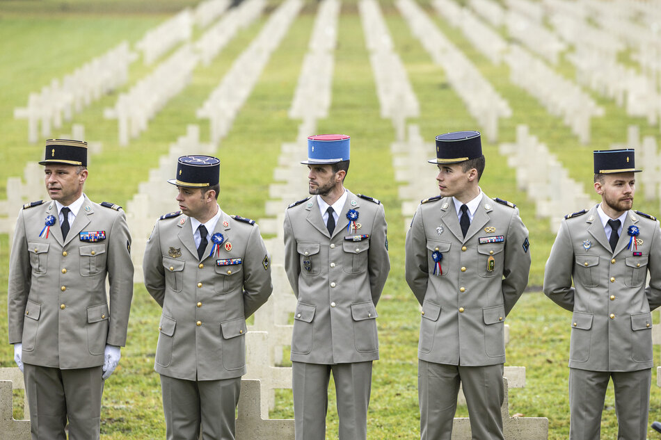 na zdjęciu pięciu żołnierzy w szarych galowych mundurach, za nimi kilka rzędów białych krzyży