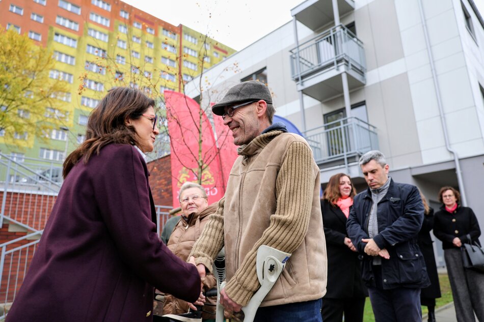 kobieta w bordowym płaczu ściska dłoń mężczyzny który opiera się na kulach inwalidzkich