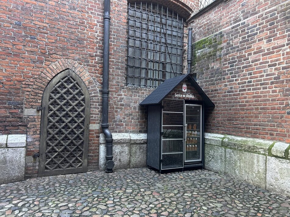 Lodówka ustawiona pod ceglana ścianą kościoła.