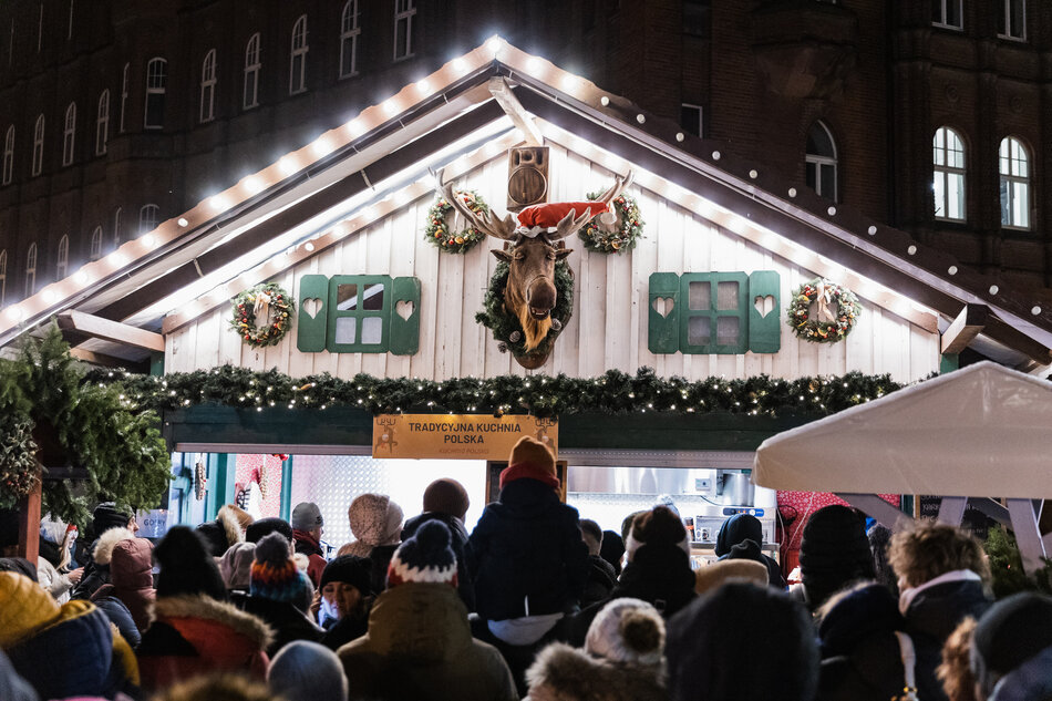 na zdjęciu chatka jarmarkowa, na górze umieszczona jest głowa łosia, przed chatką stoi tłum ludzi w zimowych ubraniach