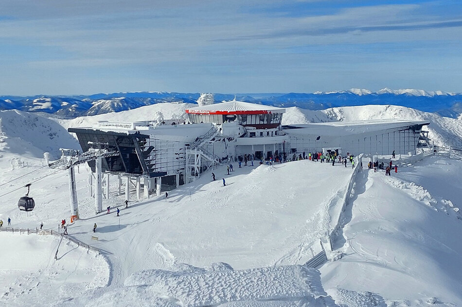 Ośnieżone góry z infrastruktura narciarską i narciażami.