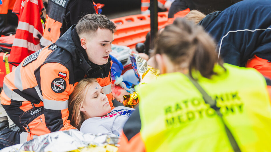 grupa ratowników podnosi na noszach młodą dziewczynę