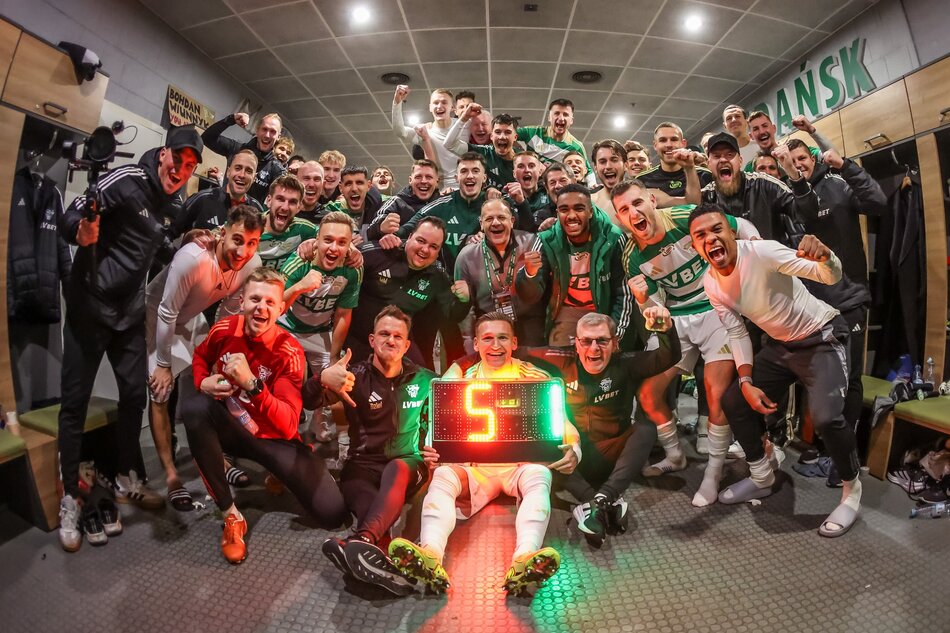 Około dwudziestu mężczyzn pozuje do zdjęcia w tryumfalnym geście