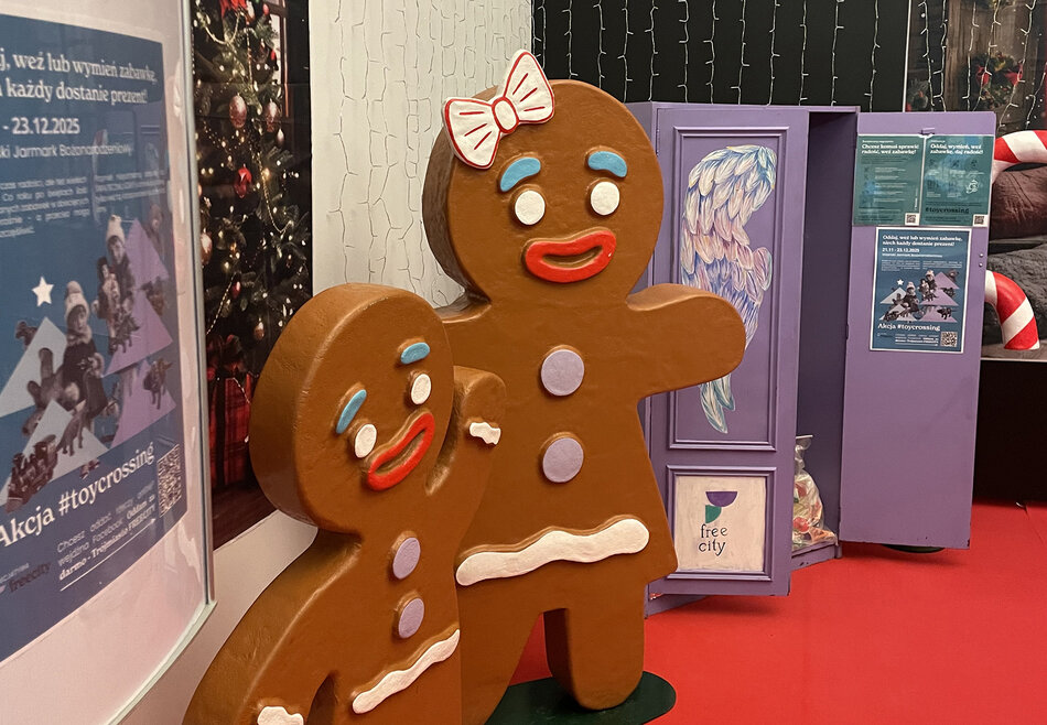 Drewniana szafa w kolorze lawendy na zabawki, obok stoją ludziki piernikowe.