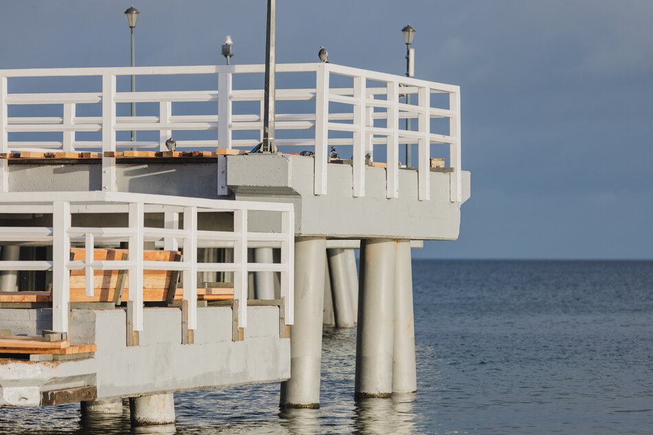 na zdjęciu fragment nadmorskiego mola, widać białe drewniane barierki