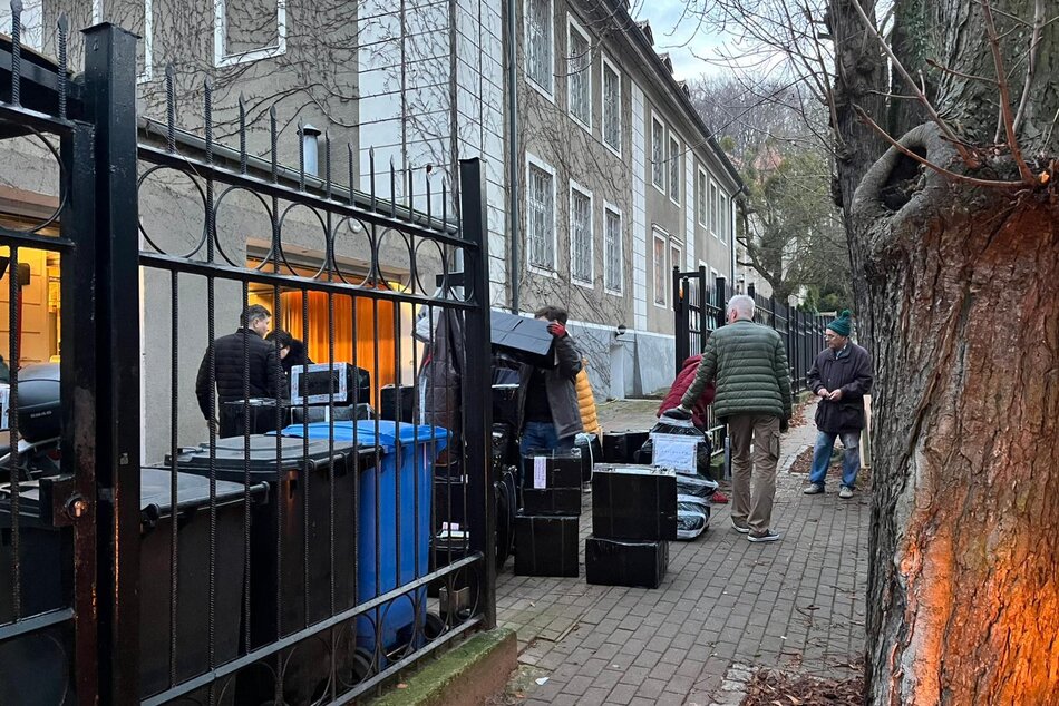 Ludzie i paczki przed budynkiem - przygotowane do zaparkowania do samochodu który stoi obok