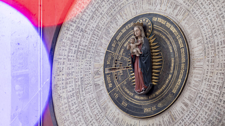  wokół podstawy znajduje się tekst, który czyta Matkę Bożą z Guadalupe w złotym napisie. Nad posągiem słowo Jezus Chrystus jest napisane mniejszymi złotymi literami. Poniżej figury wydaje się być wzór podobny do siatki z liniami i kropkami, reprezentujący znaki zodiaku. Tło jest białe, a ogólny schemat kolorów jest głównie czarny i złoty. Po lewej stronie tego obrazu widoczny jest gradient czerwony oraz niebieski, tworzący poczucie głębi i wymiaru.