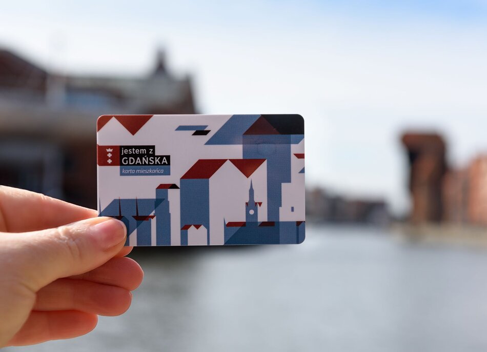 na zdjęciu ludzka ręka trzyma plastikową kartę, przypominającą bankomatową