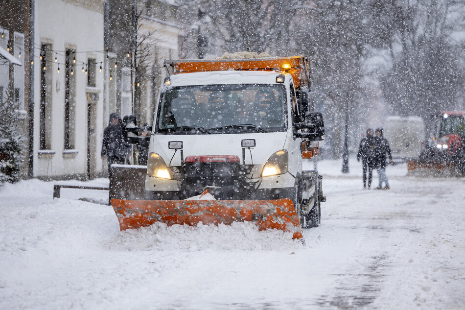 Samochód z pługiem śnieżnym na zaśnieżonej ulicy