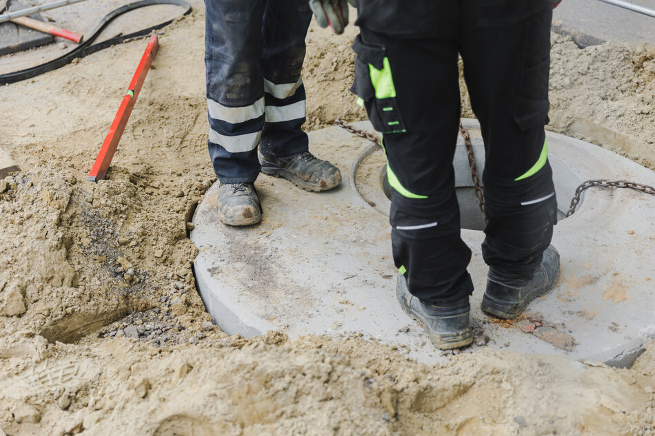 na zdjęciu dwie pary męskich nóg w granatowych roboczych spodniach