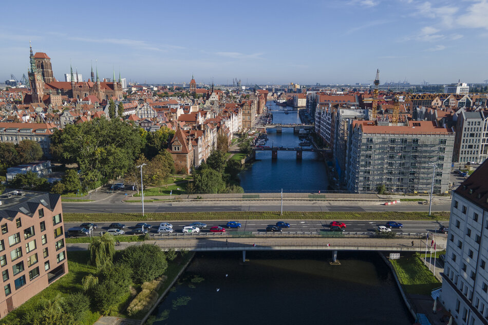 zdjęcie z drona, widać most nad rzeką, po którym jadą samochody, po obu stronach zabudowa śródmiejska