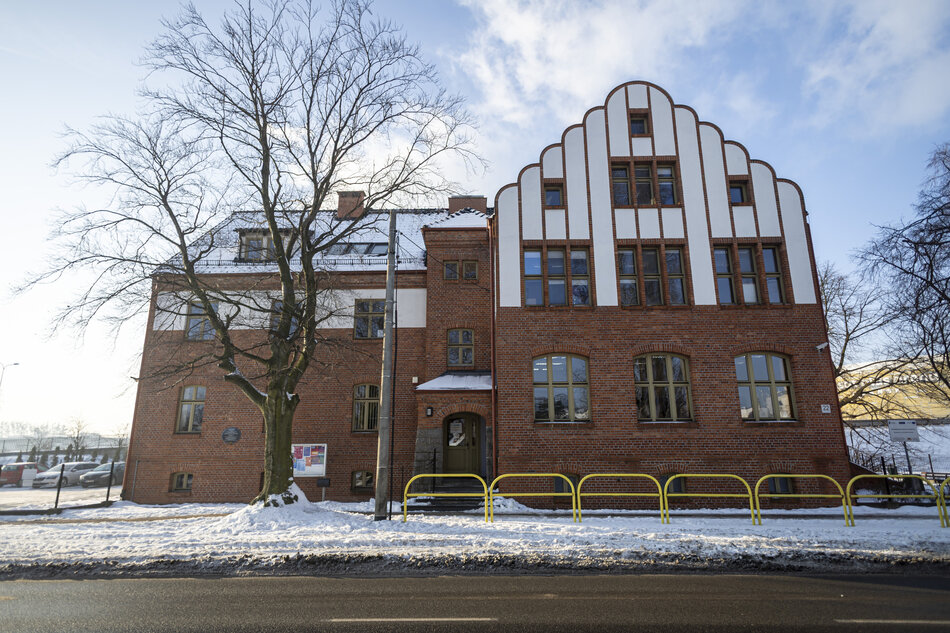 na zdjęciu zabytkowa kamienica, górna część budynku ma białą elewację, dolna - ceglaną