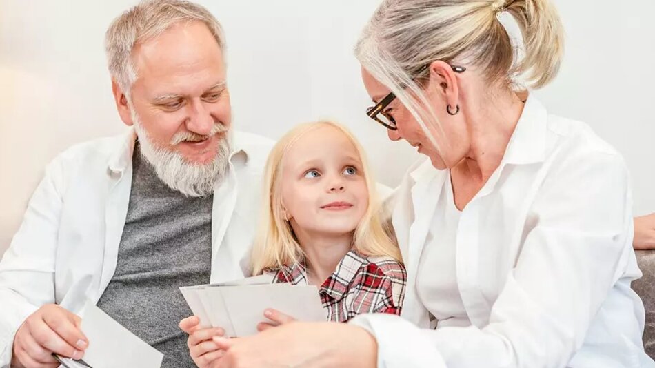 Starsza kobieta i starszy mężczyzna z dziewczynką w wieku lat około 10 - siedzą wszyscy uśmiechnięci dziewczynka między nimi