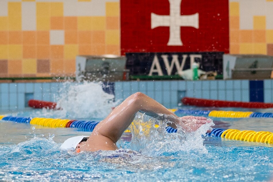 Osoba w czepku płynie na pływalni.