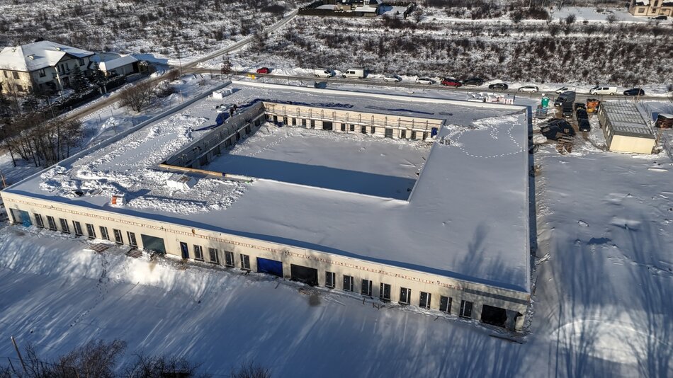 zdjęcie z drona, widać ośnieżony niski budynek w kształcie kwadratu, z otwartym wewnętrznym dziedzińcem