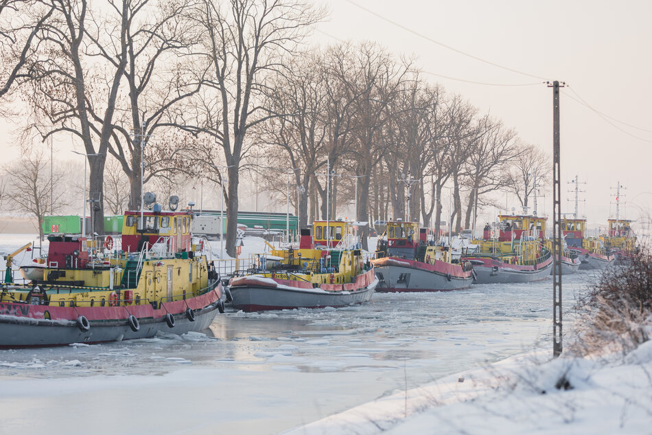 Lodołamacze cumują w porcie przy nabrzeżu na rzece skutej lodem.