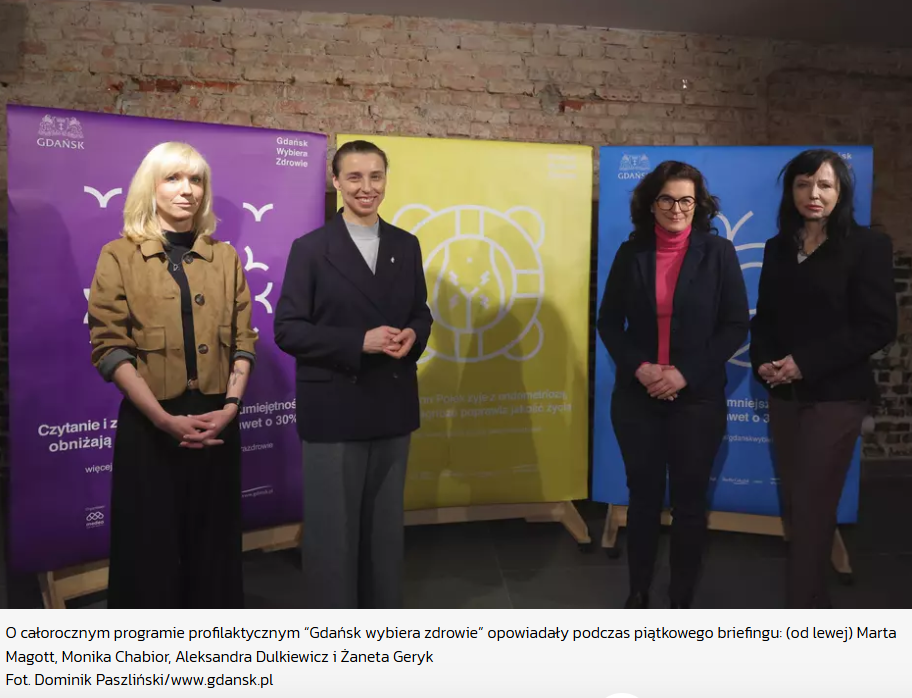 Zdjęcie z briefingu prasowego dotyczącego całorocznego programu profilaktycznego „Gdańsk wybiera zdrowie”. Na tle kolorowych ścianek informacyjnych stoją (od lewej): Marta Magott, Monika Chabior, Aleksandra Dulkiewicz i Żaneta Geryk.