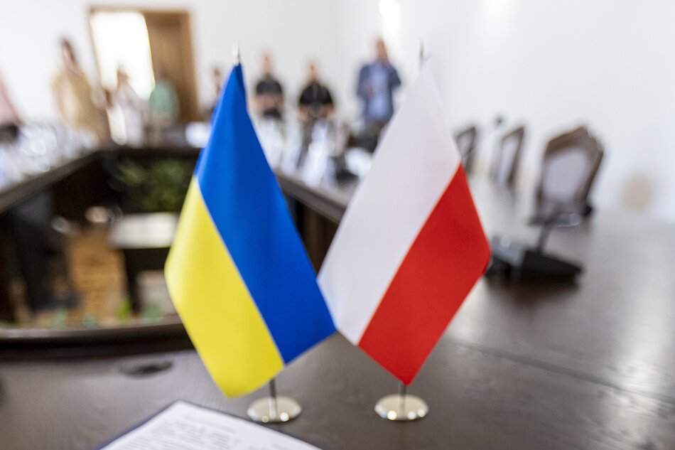 Zdjęcie dwóch chorągiewek na stole konferencyjnym - polskiej i ukraińskiej 