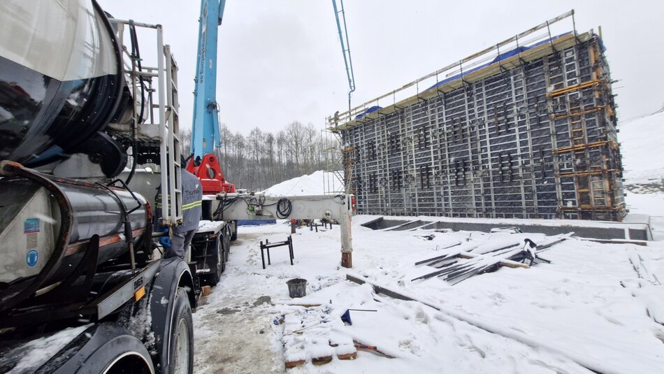na zdjęciu po prawej powstający przyczółek mostu owinięty czarną folią, po lewej ciężarówka