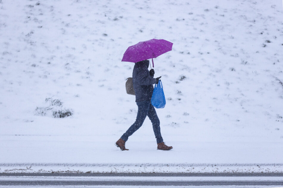 kobieta z fioletowym parasolem. Idzie w śnieżnej scenerii podczas opadów śniegu