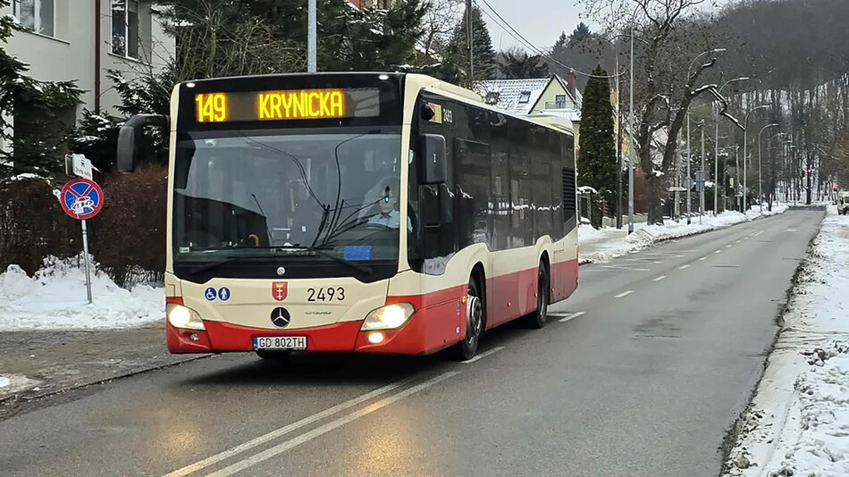 Autobus linii 149 jedzie ulicą starego miasta, na poboczu leży śnieg, w tle widać wzgórze i las.