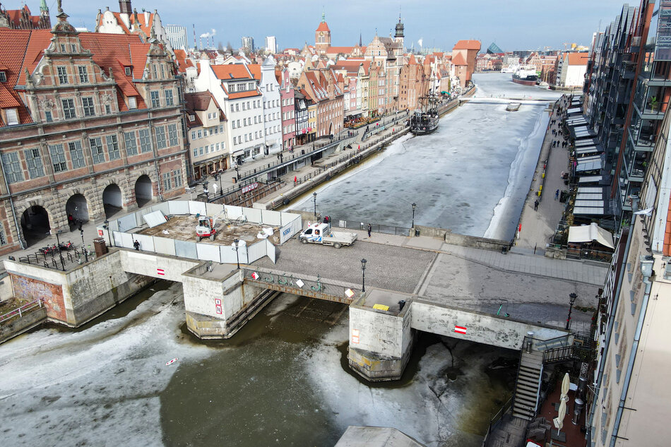 zdjęcie z drona widać zabytkowy most zielony, a na nim ogrodzenie placu robót i koparkę, w tle zabudowa gdańskich kamienic