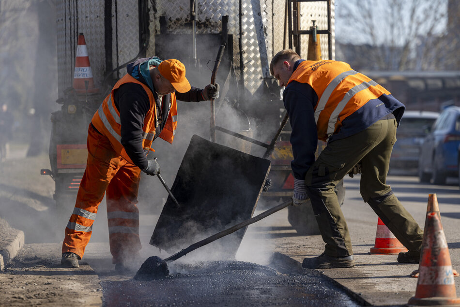 na zdjęciu dwóch mężczyzn robotników naprawia nawierzchnię jezdnię