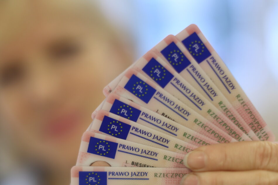 Dłoń trzyma kilka praw jazdy ułożonych jak karty do gry