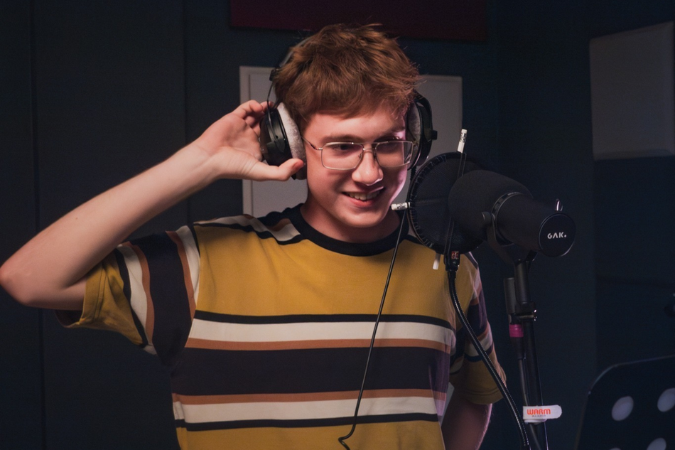 Młody mężczyzna stoi przy mikrofonie ze słuchawkami