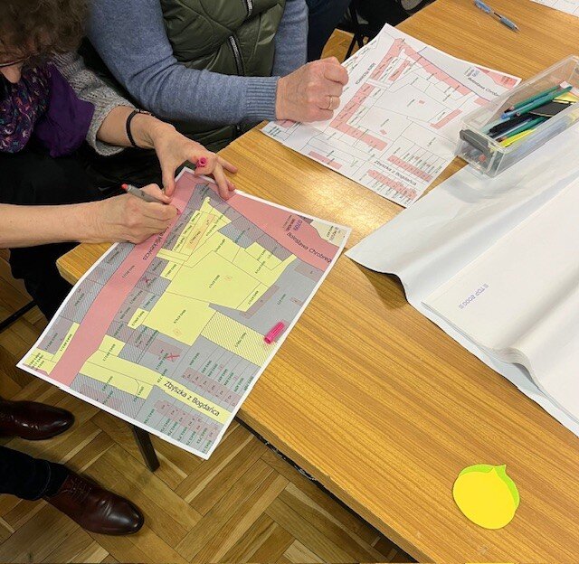 na zdjęciu dwie ludzkie ręce wskazują coś na papierowej kolorowej mapce