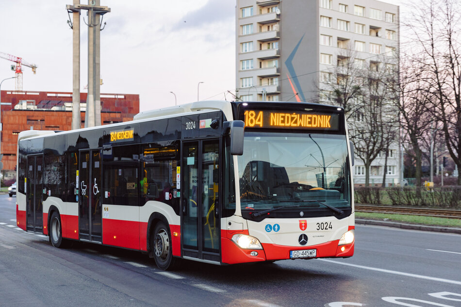 autobus czerwono-biały na ulicy miejskiej. Autobus marki Mercedes-Benz z numerem 304 z przodu i napisanymi na nim słowami 184 Niedźwiednik