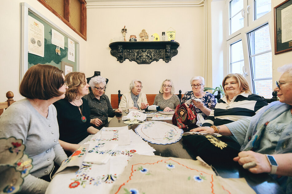 Kobiety siedzą przy stole i haftują