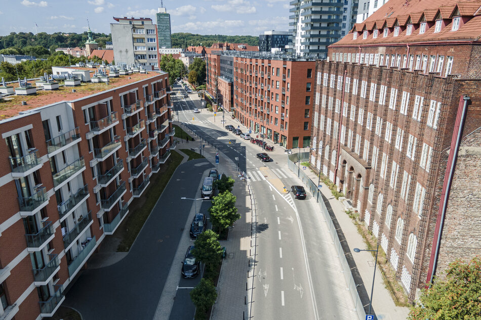 gęsta miejska zabudowa, po obu stronach ulicy wysokie budynki o ceglanej elewacji