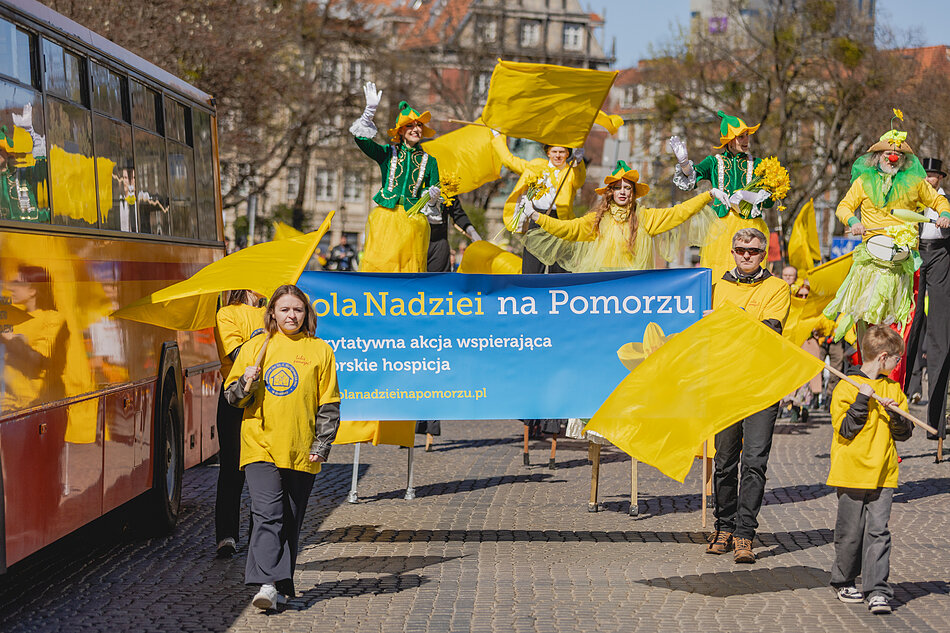 Duża grupa osób ubranych na żółto lub niosących żółte flagi i transparenty - idą ulicą