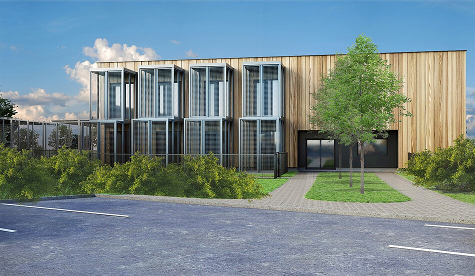 Obraz przedstawia nowoczesny, piętrowy budynek o elewacji łączącej jasne drewno z ciemnymi elementami wykończenia. Charakterystycznym punktem konstrukcji są przeszklone moduły z metalowymi kratownicami, które pełnią funkcję zabezpieczonych balkonów lub wybiegów.