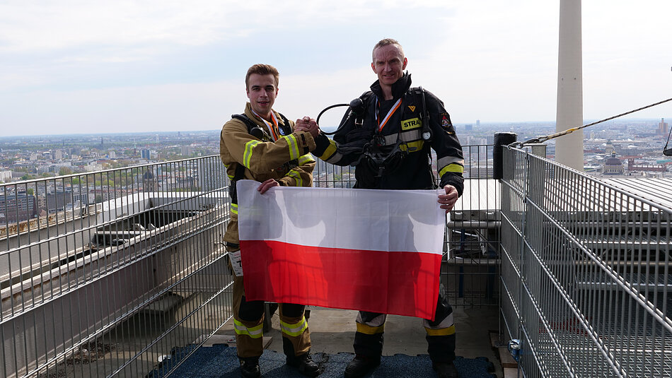 Strażacy trzymają polską flagę w Berlinie 