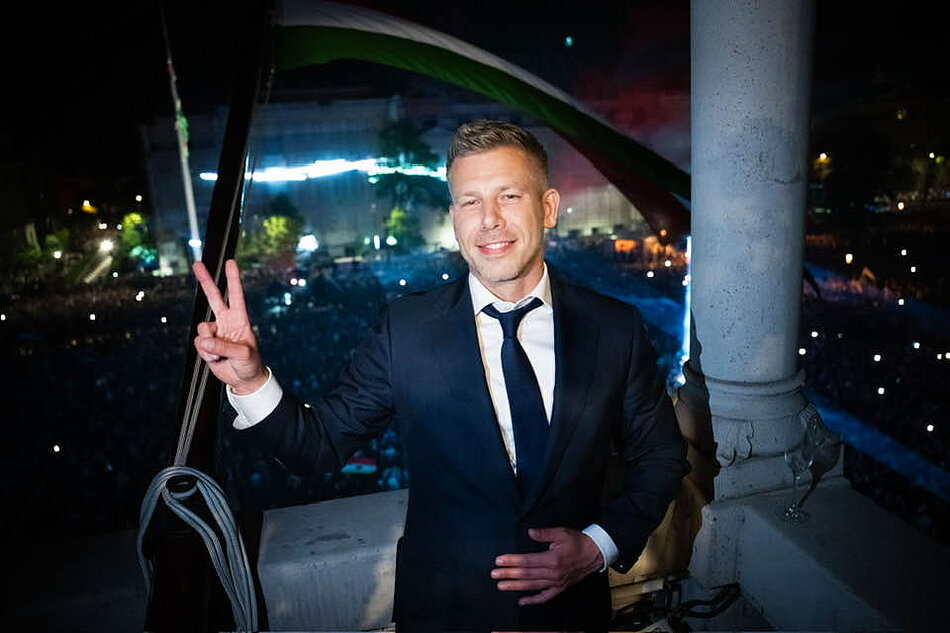 Magyar na tle wiecu wyborczego, palce dłoni układa w literę V