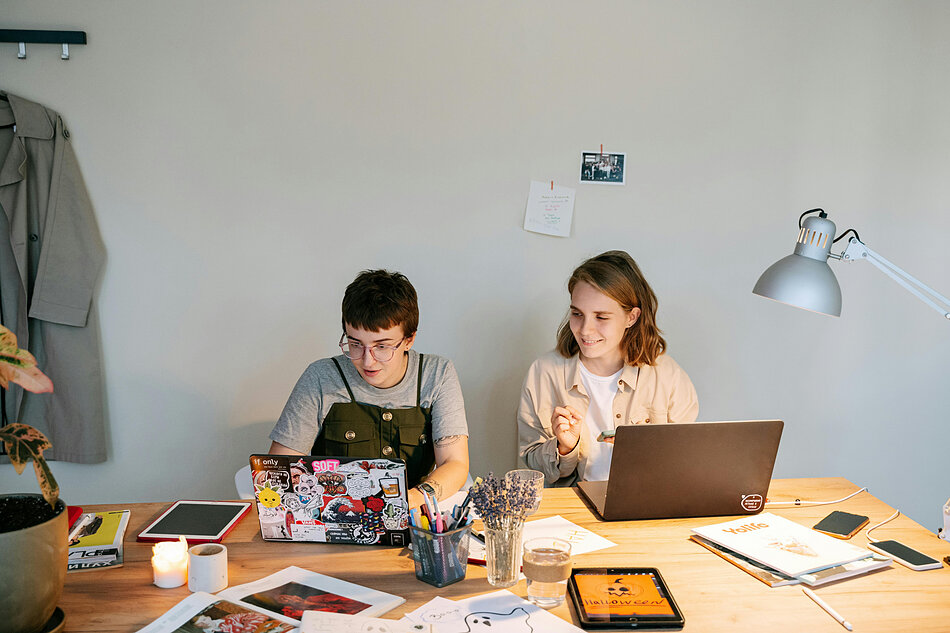 Ludzie siedzą przy laptopach i piszą.