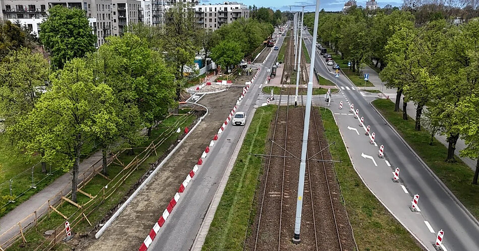 Zdjęcie z lotu ptaka, widok na dwupasmowa jezdnię z torowiskiem pośrodku.