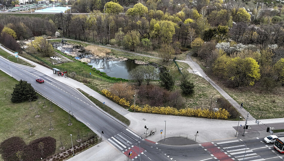 zdjęcie z drona, widać duży zbiornik retencyjny w formie stawu, wypełniony wodą, wokół dużo zieleni