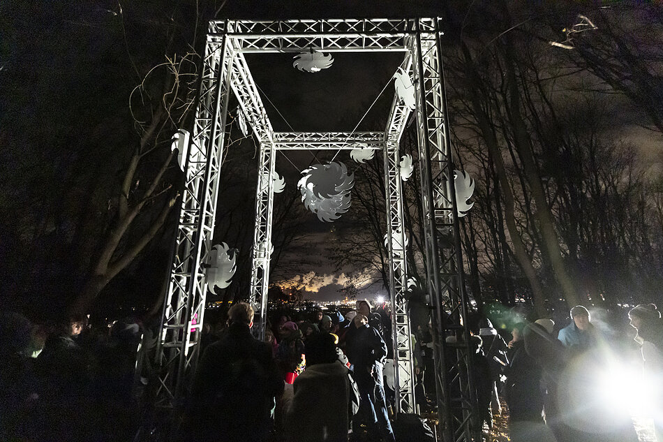 Ludzie przy instalacji artystycznej w mieście wieczorem.