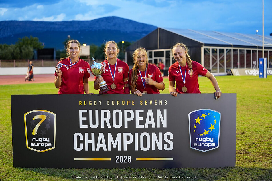 Rugbystki w czerwonych koszulkach trzymają puchar