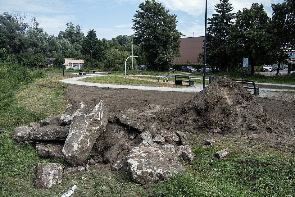 Zieleniec w mieście przygotowany pod nasadzenia, obok góra ziemi i gruzu.
