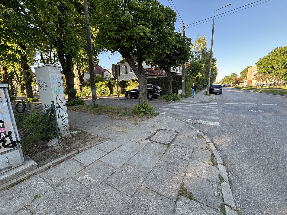 fragment jezdni i chodnika, w tle budynek