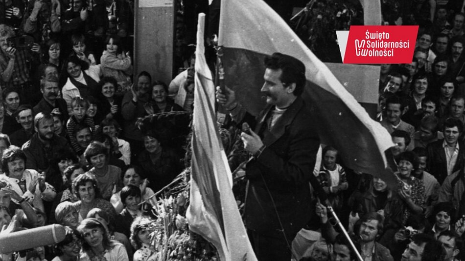 Wałęsa przemawia z wysokości szczytu bramy, która z obu stron otoczona jest tłumem ludzi