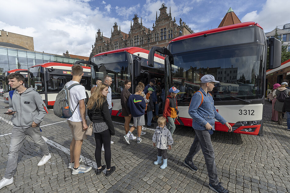 Ludzie oglądają na miejskim placu nowe autobusy.
