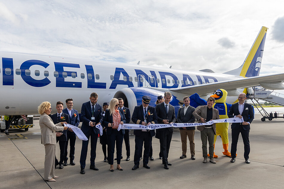samolot icelanair stoi na płycie, załoga samolotu i witający pozują z przeciętą wstęgą z napisem first flight